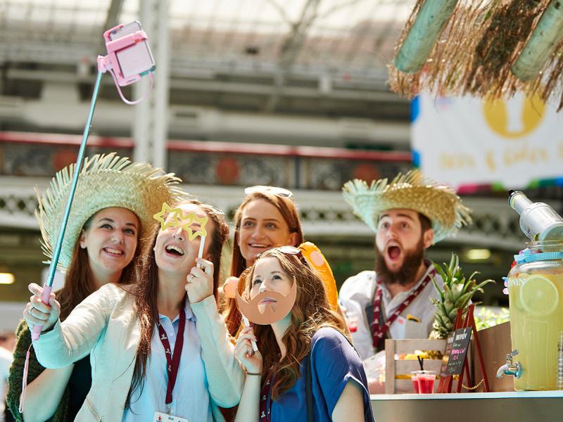 Group of visitors taking a picture at an event using a selfie stick