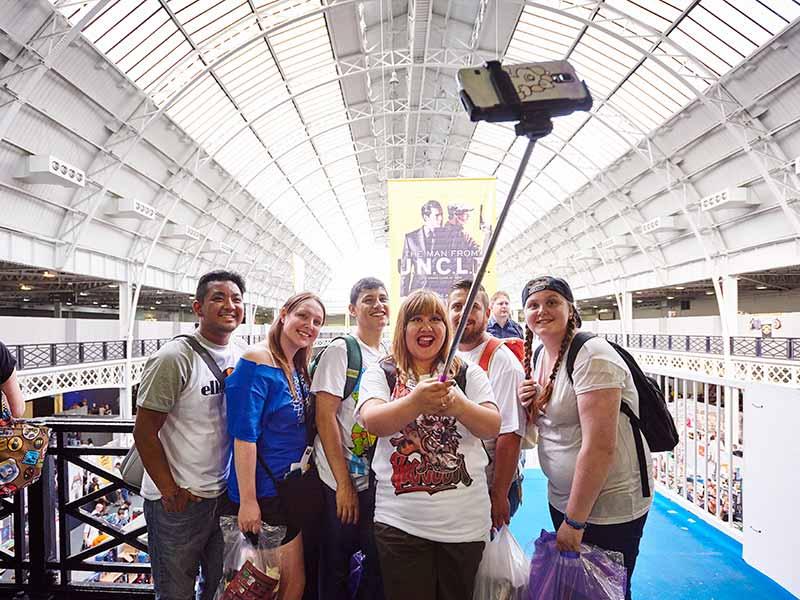 Group of visitors taking a picture at an event using a selfie stick