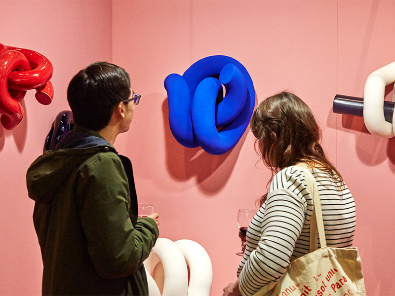 Two individuals observing a collection of sculptures displayed in an art gallery setting.