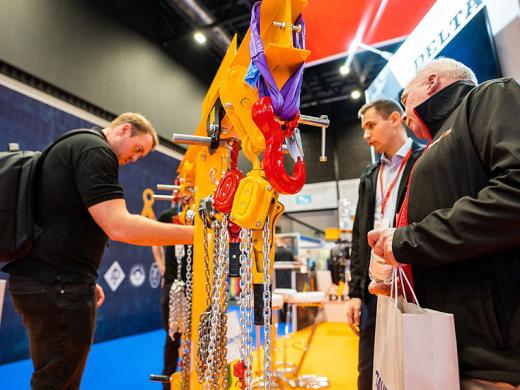 Three men examining a display of lifting chains.