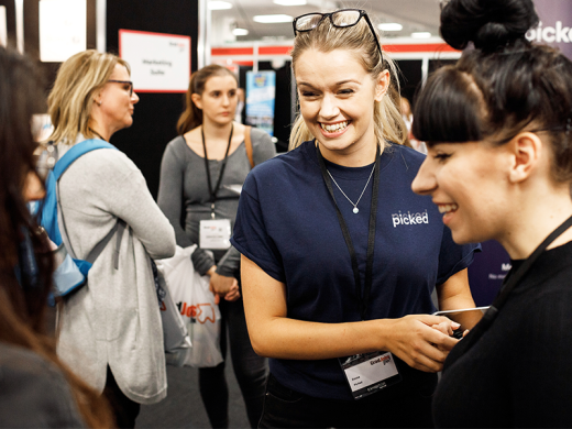 A woman engages in conversation with another woman at a trade show.