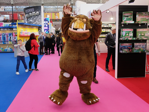 A cheerful mascot dressed in a bear costume engaging with attendees at a lively event, spreading joy and excitement.