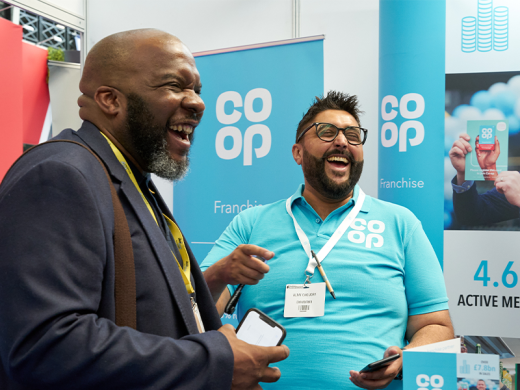 Two men laughing, engaged in conversation at a trade show.