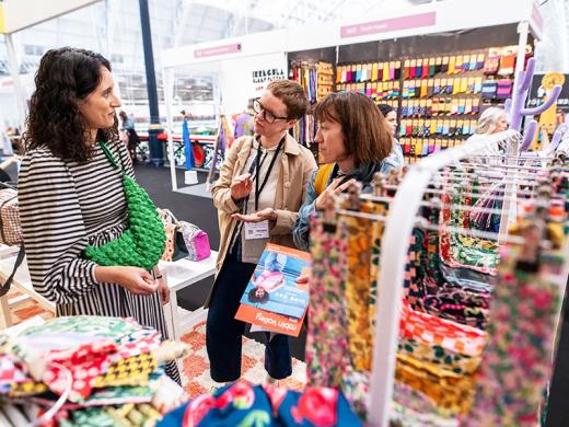 Three women examine various fabrics while shopping in a store, showcasing their interest in textiles and design choices.