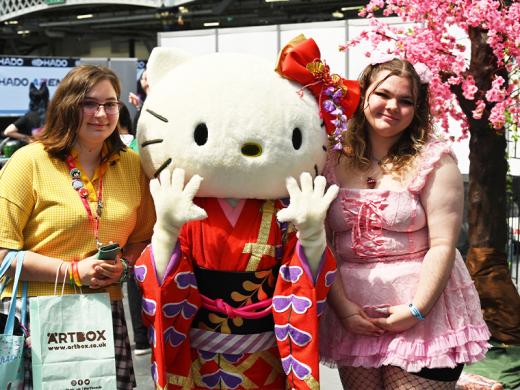 Two women pose beside a Hello Kitty mascot.