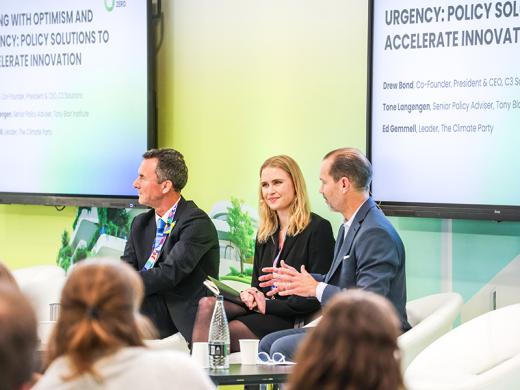 Four panelists are seated on stage at a conference, engaged in conversation.