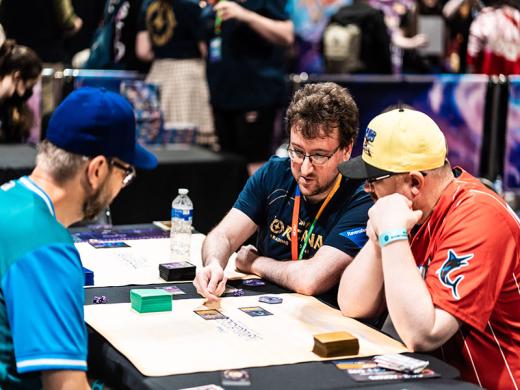 Two men talking to another man about card trading at the Card Trading Convention