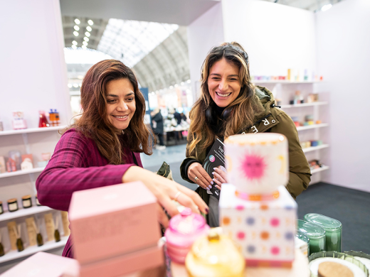 Two women looking and lifting items from a display at Top Drawer