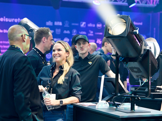 A woman talking with a man whilst looking around the exhibitor stands at PLASA