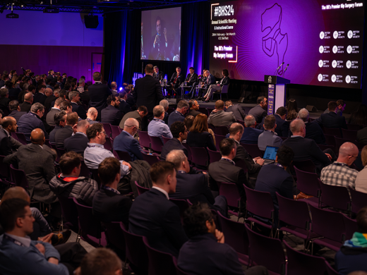 A panel on stage presenting to a large audience