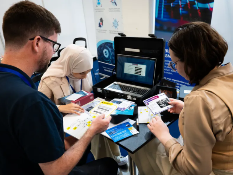 Three people sitting at a table with laptops, engaged in work and collaboration.