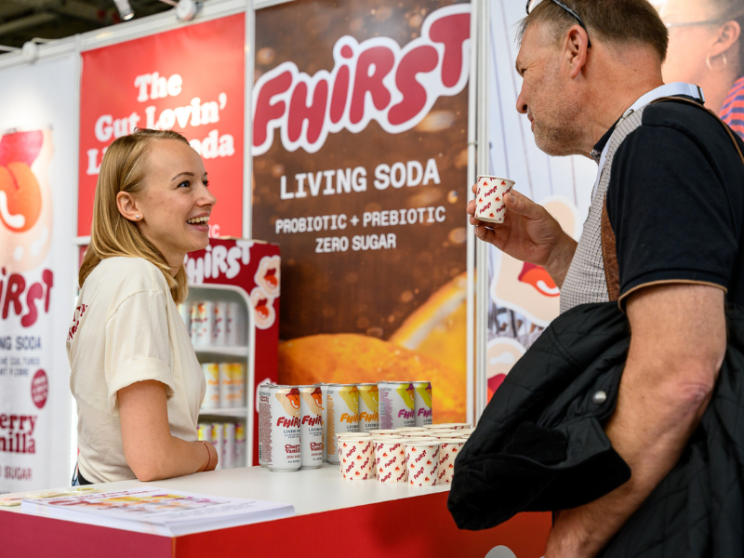 A man and woman standing at a booth during a trade show.