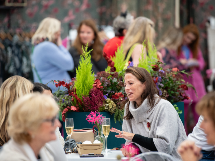  A woman sitting at a table with other people, engaged in conversation and enjoying each other's company.