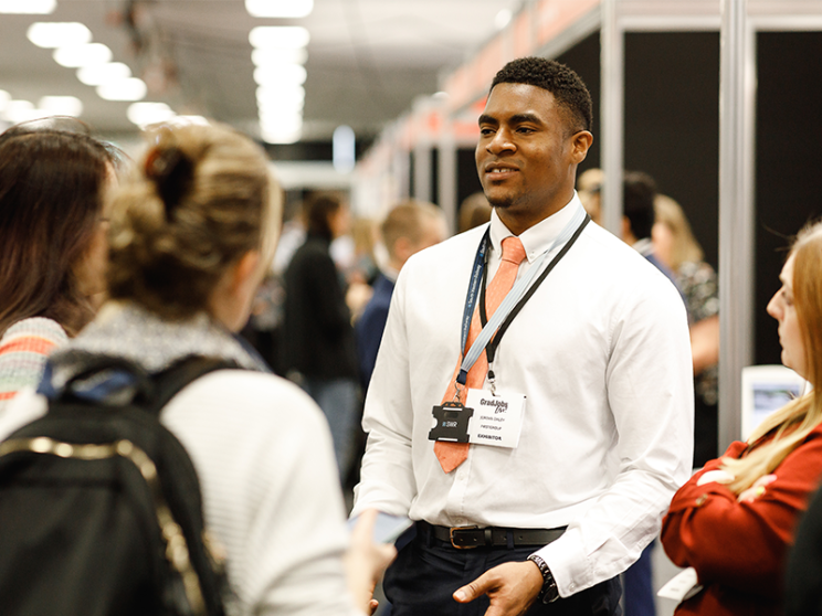 A man engages with attendees at a trade show.