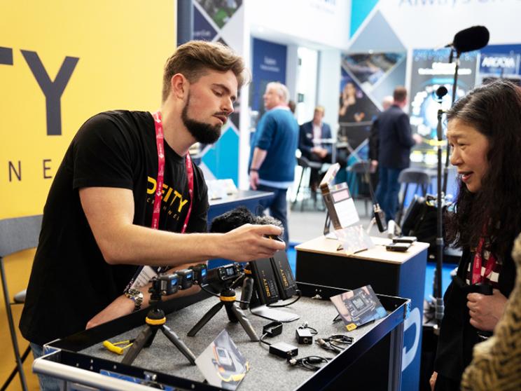 A man and woman are smiling, exploring a piece of camera equipment.