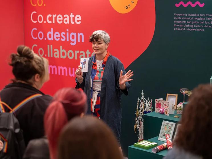 A woman engages with attendees at an event, sharing insights and fostering connections among the participants.