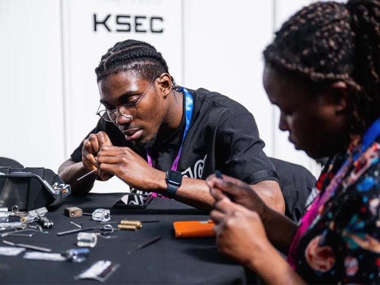  Two individuals collaborating on electronics projects at a table.