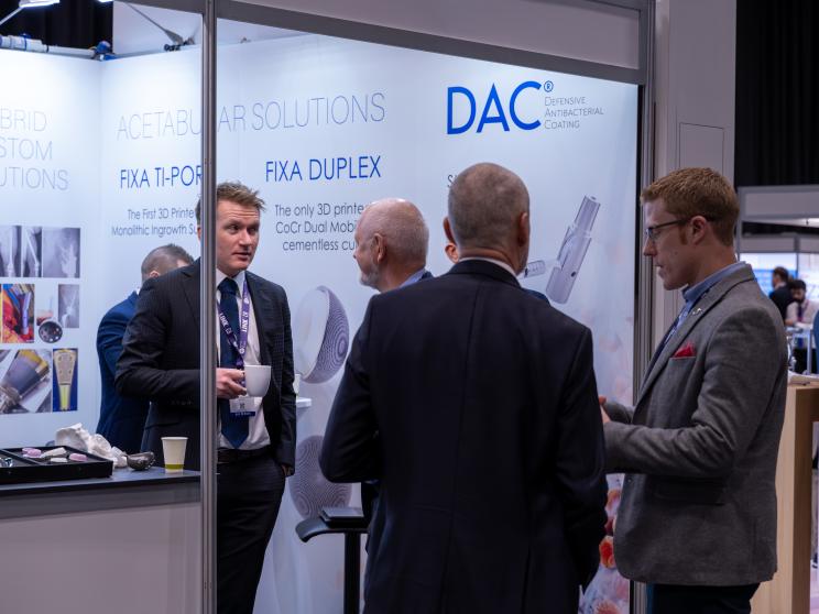 Four men engaging in conversation around an exhibition stand