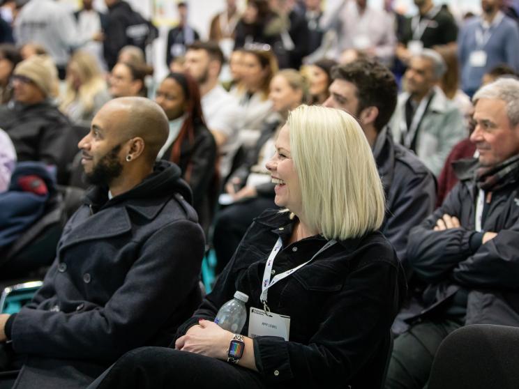 Two people smiling engaged with the presentation on stage