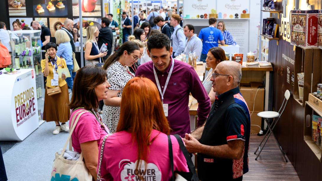 People networking at a trade show, engaging in conversations and exploring various booths and exhibits.