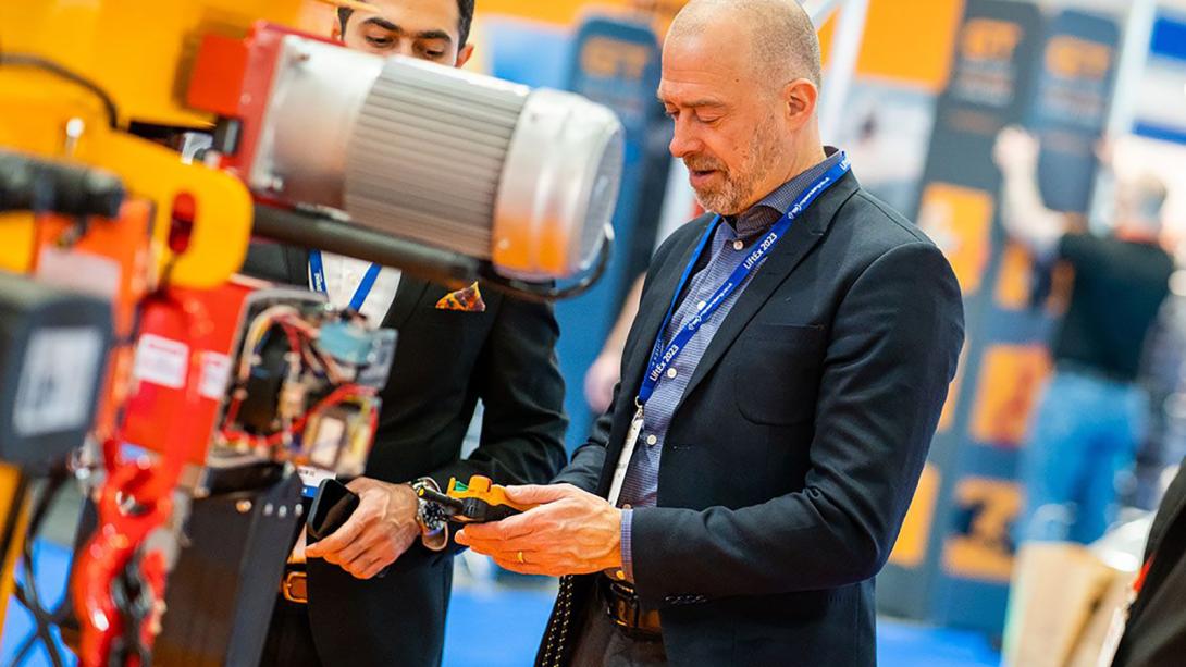 Two businessmen in suits inspecting a lifting machine.