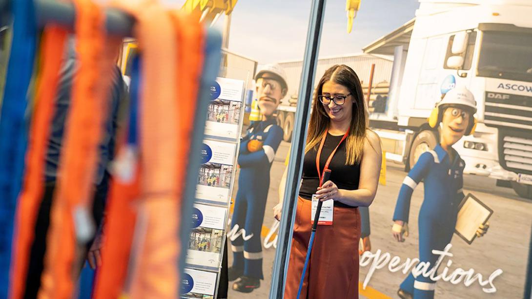 A woman standing in front of large display of lifting equipment.