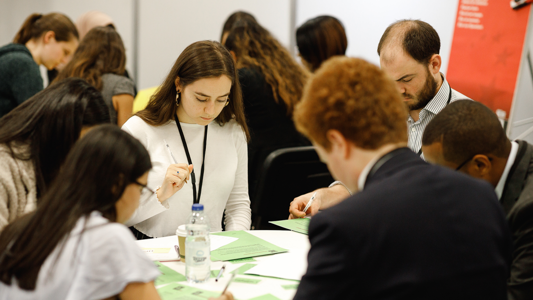 Several people gather at a table, examining papers.