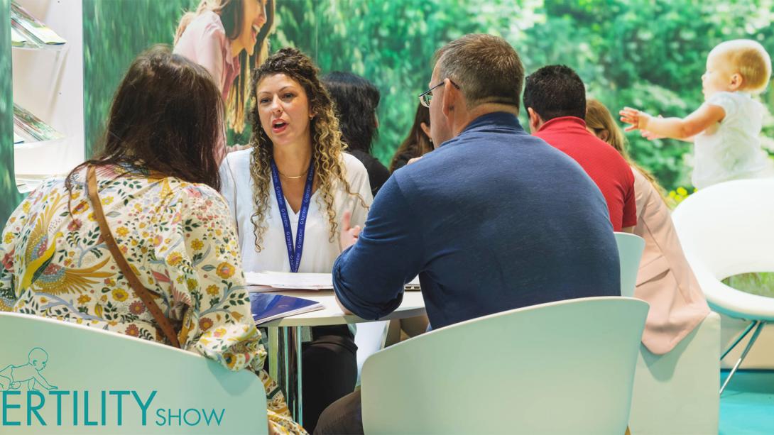 Attendees engaged in discussions while seated at tables during a fertility show event.