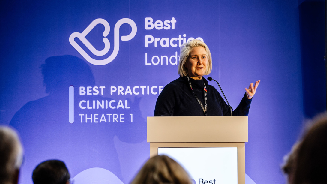 A woman speaking at a podium, with the words "Best Practice London" visible in the background.