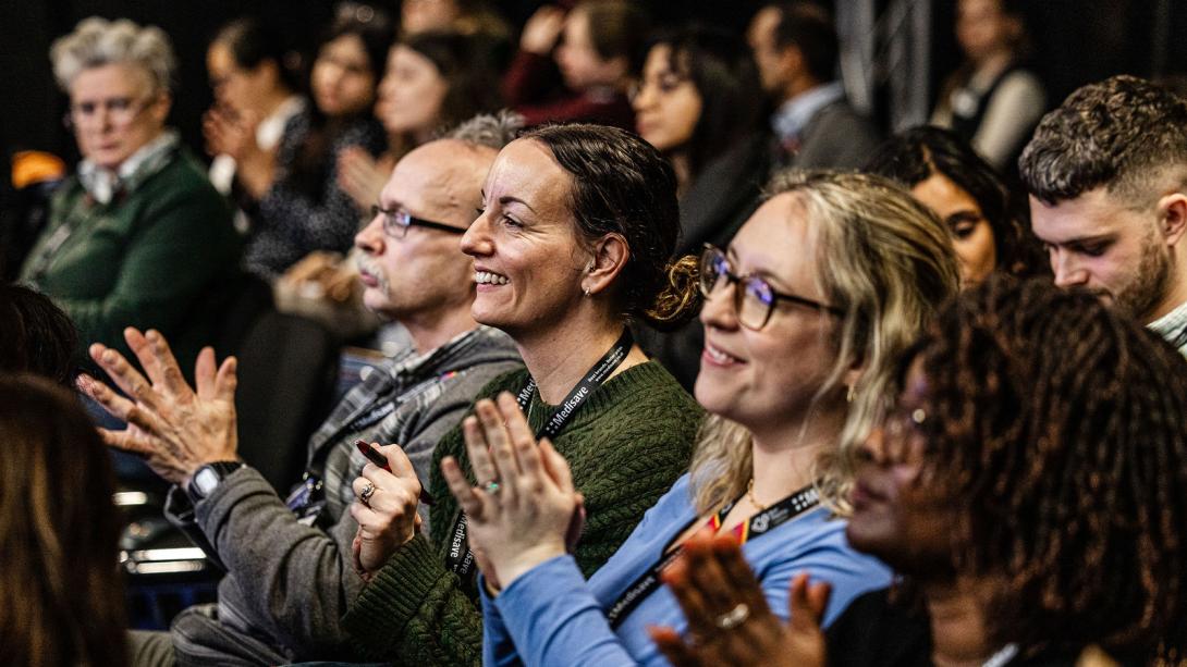 A crowd of conference participants clapping.