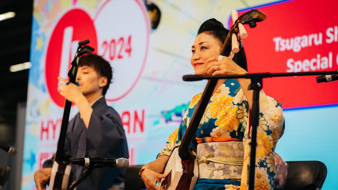 Two individuals in traditional kimonos playing musical instruments.