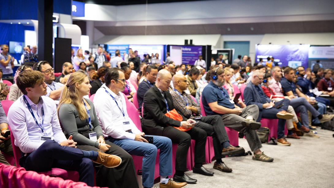 A large crowd of attendees seated in chairs, engaged in a conference setting.