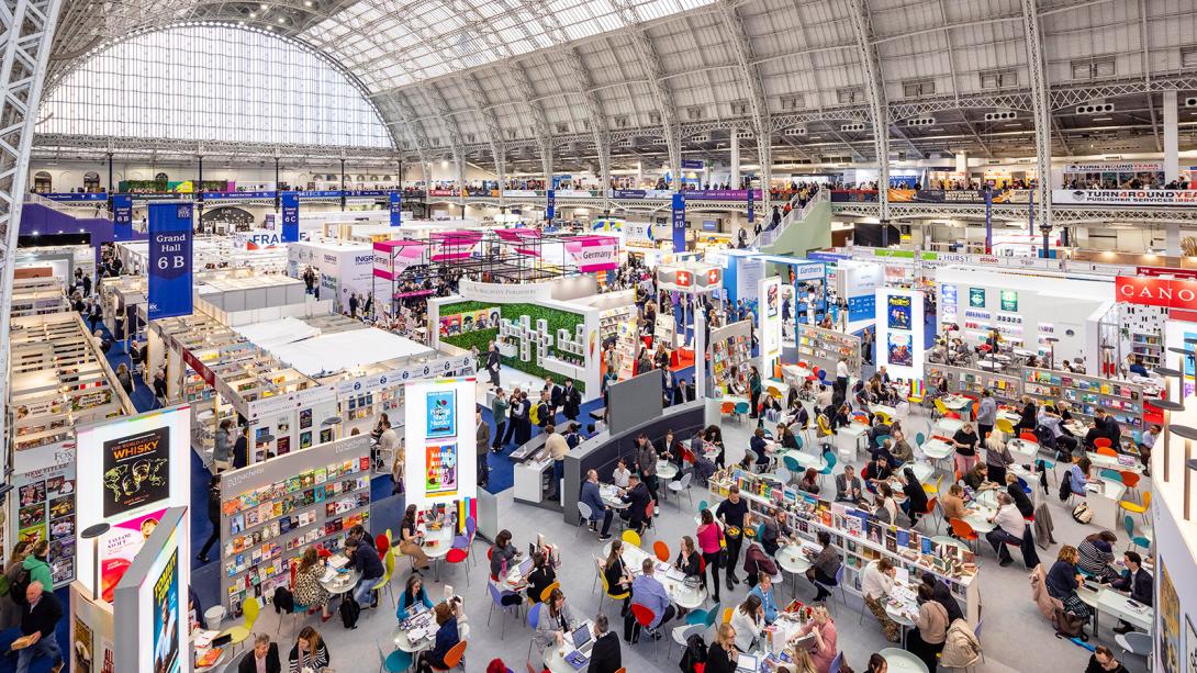  A bustling indoor event filled with people browsing a wide selection of books on display.