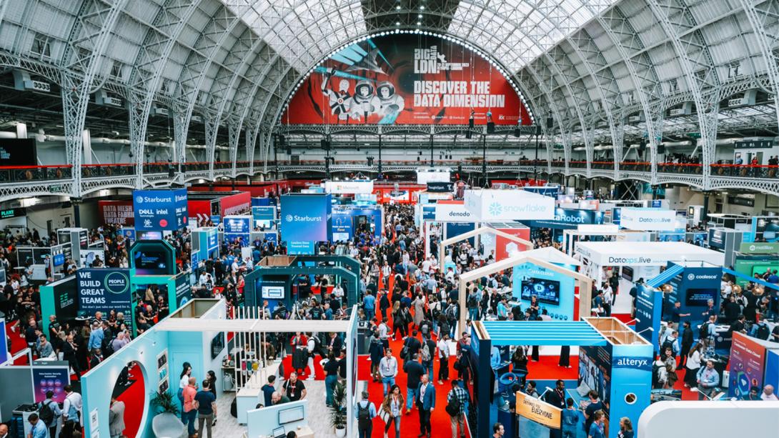 A large crowd gathers in a spacious indoor hall at a large tech event.