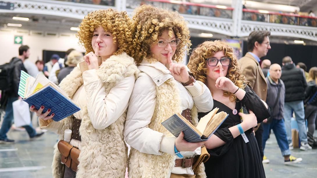 Three women in elegant fur coats, each holding a book, exuding sophistication and style.