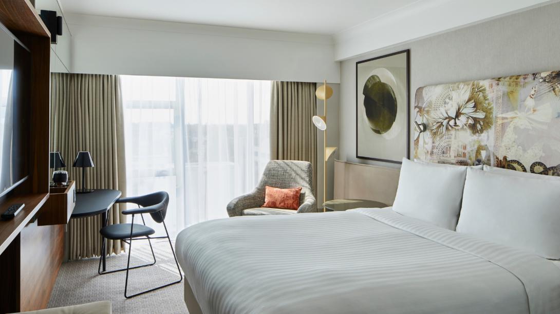 A hotel room featuring a bed, a television, and a chair, creating a cozy and inviting atmosphere for guests.