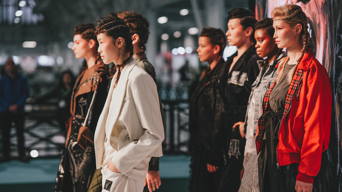 A group of catwalk models standing together about to walk down the catwalk