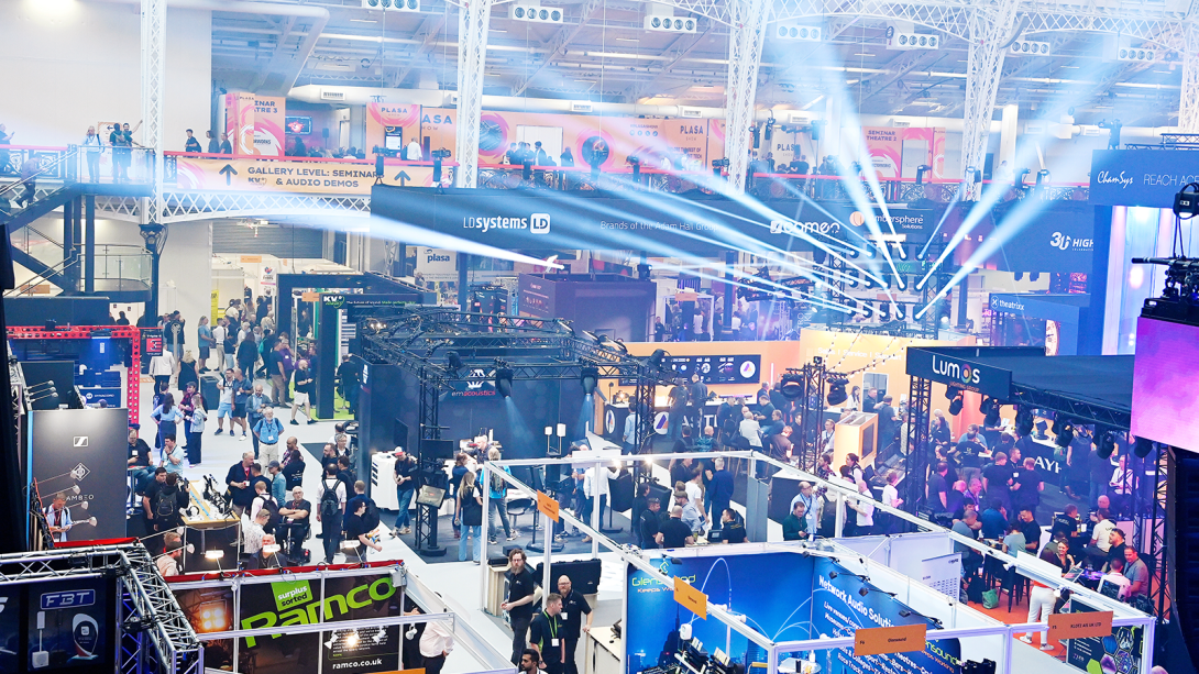 People gathering around show floor taking an interest in the exhibitor stands and showcases