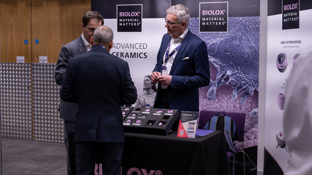 Three men stood around an exhibition stand engaging in conversation