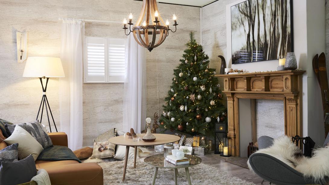 Interior of a cozy living room decorated for Christmas, featuring a decorated tree, a fireplace, and festive ornaments.
