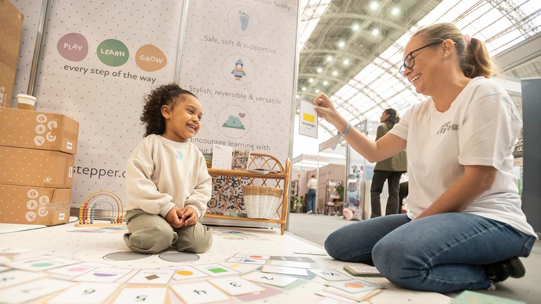 A woman sitting and interacting with a baby at The baby show