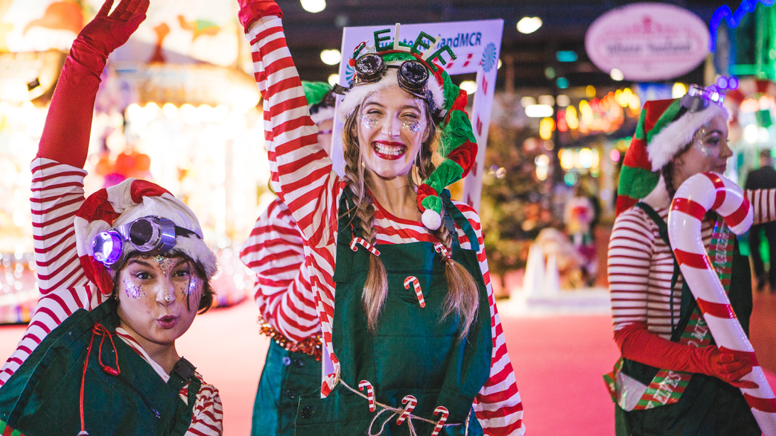 Two women dressed as elves smiling and posing at the camera