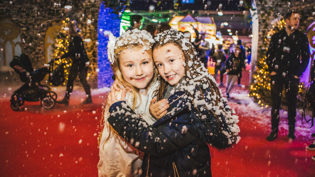 Two little girls smiling at camera and hugging with snow on them